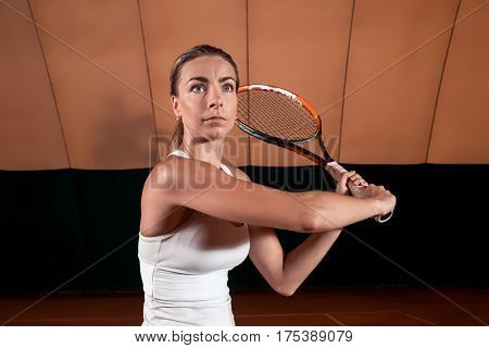 Sportswoman at the tennis court with racquet. Indoor tennis court