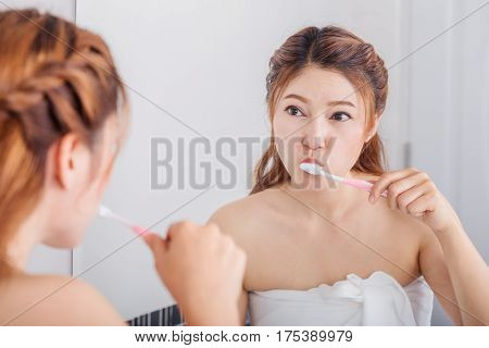 Woman Cleaning Mouth Using Toothbrush With Mirror In Bathroom