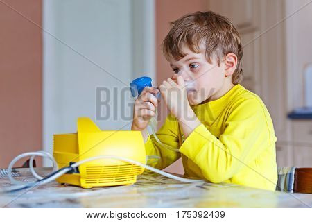 Cute boy making inhalation therapy by the mask of inhaler. Close up image of a little sick kid. Sad child with clear oxygen mask.