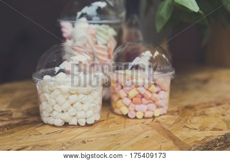 Desserts choice. Marshmallow chewing candies in glass jars on counter bar. Traditional american sweets for sale, closeup