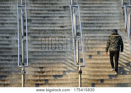 A youth with a camouflage jacket goes up a staircase.