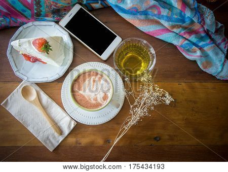 coffee cup and delicious cake strawberry and relax time moblie on table in coffee shop