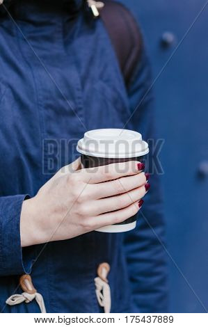 Cup of coffee to go in the hand of a young woman.