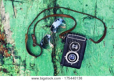 Old retro camera with sunglasses on vintage wooden boards abstract background