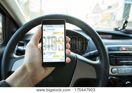 Person Sending Text Message On Mobilephone While Driving The Car