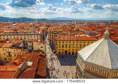 Panoramic view Baptistery of San Giovannito in Florence and tile roofs old town houses. Green hills blue sky with clouds summer landscape on background. Firenze, Italy.