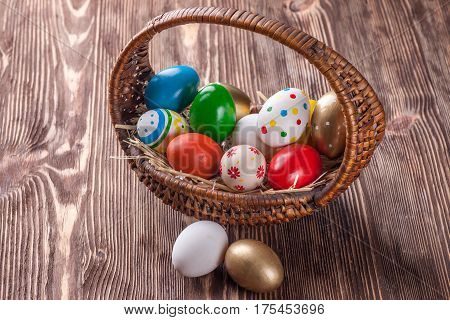 Colorful easter edds in basket on a brown wooden table