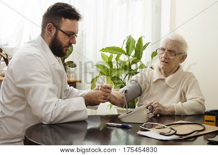 Measurement of pressure. The doctor geriatrician. Care for old people. Medical home visit with his grandmother.