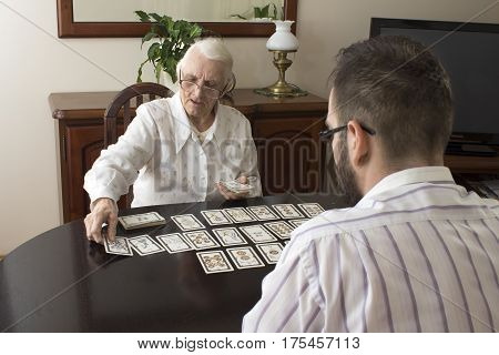 Grandma puts tarot grandson. 
Age fairy puts tarot cards 
Very old woman puts a man tarot cards. 
Fortune-telling with tarot cards.