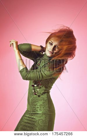 Colorful studio portrait of a beautiful young woman with flowing hair on a rose background