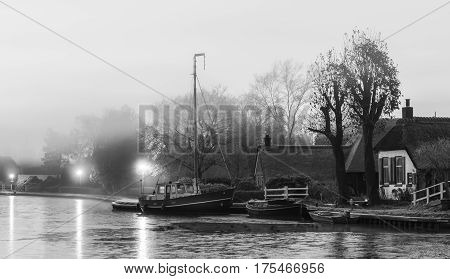 Kalenberg and the Kalenbergergracht during sunrise with farmhouses boats a bridge and ducks.