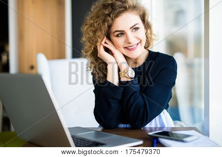 Young Attractive Woman At A Modern Office Desk, Working With Laptop, Looking At The Window, Thinking