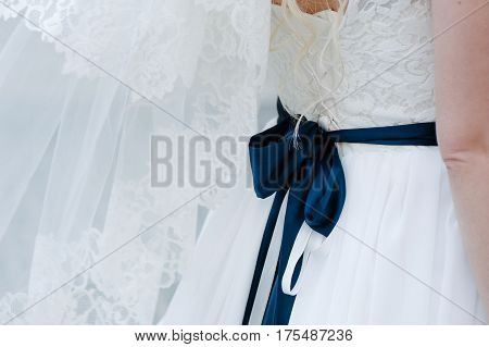 Big, dark blue bow on bride white, tenderless dress closeup