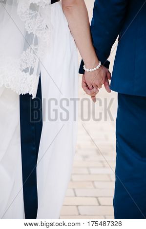 Newlyweds staying togeser and holding arm in arm, outdoor close-up