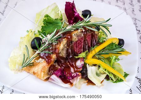 Veal with mushrooms in puff pastry and vegetables on a white plate