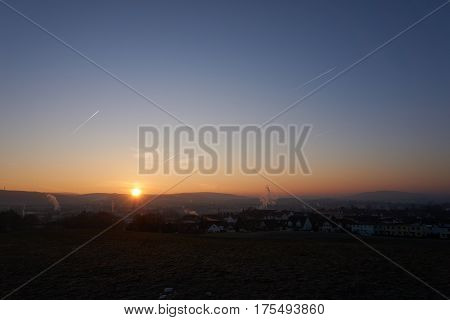 sunset with smoke and condensation trails on a business day