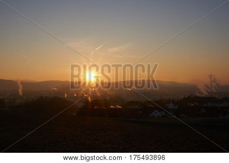 sunset with smoke and condensation trails on a business day