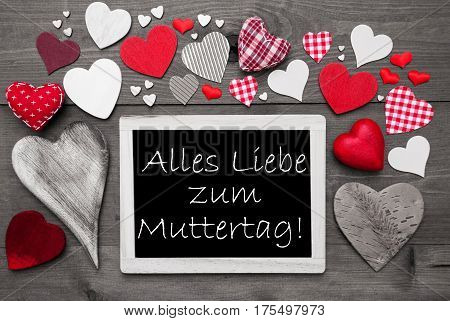 Chalkboard With German Text Alles Liebe Zum Muttertag Means Happy Mothers Day. Red Textile Hearts. Grey Wooden Background With Vintage, Or Retro Style. Black And White Style With Colored Hot Spots