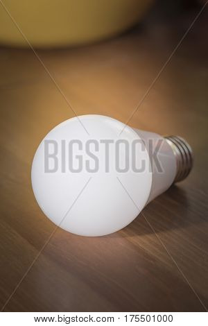 Burning light bulb with frosted glass lying on a brown desk without a network connection