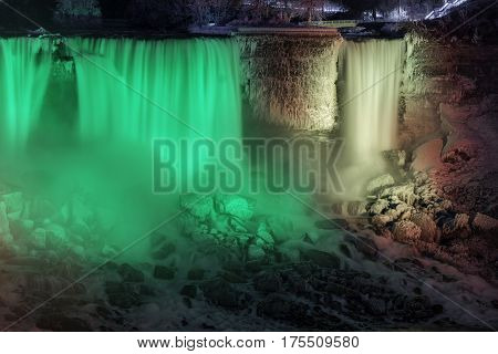 Closeup of Niagara Falls american side at night beautifully illuminated in green and red winter scene with snow and ice