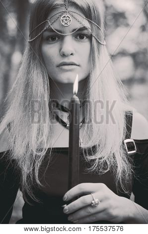 Young witch with pink hair performing a magical ritual with a black dark candle black and white photo faded colors selected focus