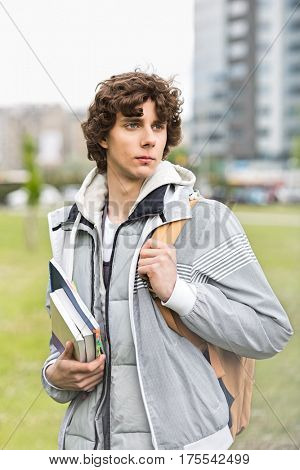 Young male university student holding textbooks at campus
