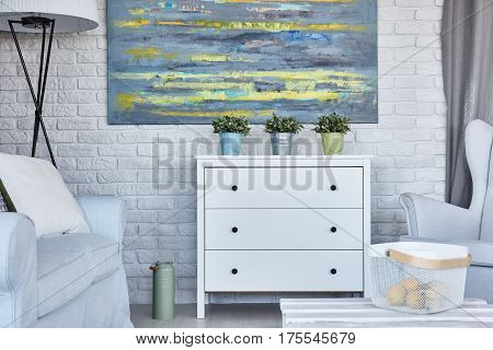 Modern room with white brick wall, oil painting, and chest of drowers, room in white colors