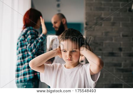 Sad Child Covering His Ears With Hands During Parents Quarrel.