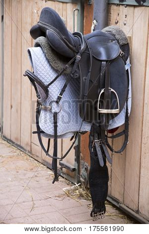 Leather sport saddle hanging in the stable for equestrian sport