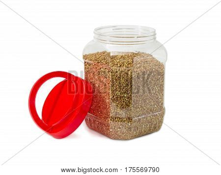 Buckwheat groats peeled from the husk in the transparent plastic container with the open red cover on a light background