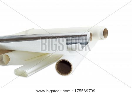 Several rolls of the plastic oven bags plastic food wrap aluminum foil and various parchment paper for household use on a light background.