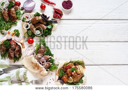 Grilled meat meals on white wooden table. Assortment on hot barbecue food assortment, free space. Restaurant menu, gourmet, lunch time concept