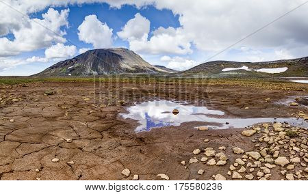Patternd ground with mud cracks in beautiful primordial icelandic landscape on a clear sunny day with blue sky and white clouds. Kaldidalur, Iceland.