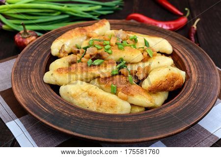 Popular traditional Czech Hungarian German dish: potato knedli (dumplings) with slices of fried bacon spicy red pepper and green onions.