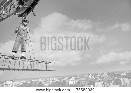 Not scared of heights. Black and white shot of a retro builder standing on a crossbar at construction site looking away thoughtfully toward copy space. high city professional worker industry engineer concept.