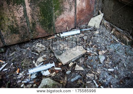 Syringes used by drug addicts in the garbage pile on the ground.