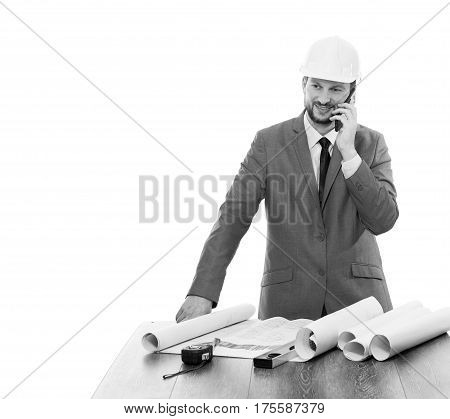 Mature male businessman engineer in a hardhat smiling talking on his phone looking away with copy space. Project planning architecture professional communication concept. Black and white.