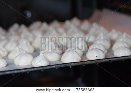 White mini meringue in baking sheet, side view