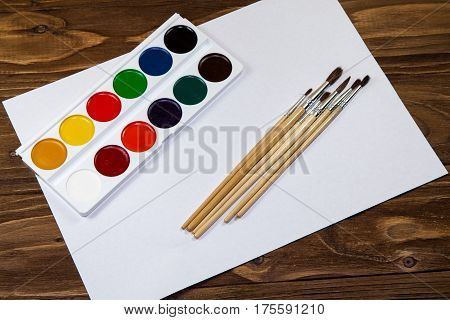Art palette with brushes and paints on a wooden background