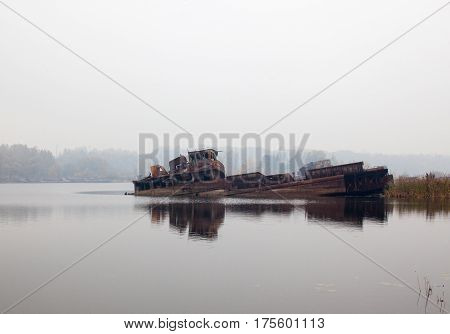 Old rusty sunken ship in water in a foggy day.