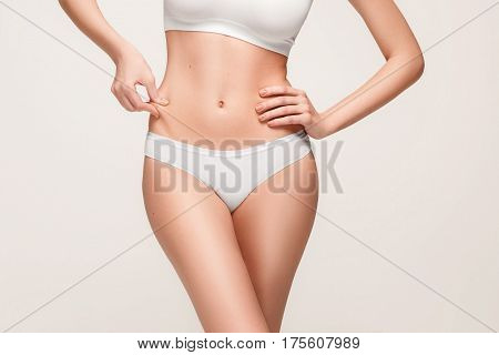 Young, slim, healthy and beautiful woman in white lingerie isolated on the white background. hips and waist girl shot closeup
