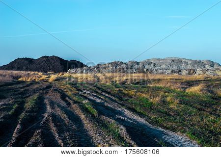 Dirt road in the field. Earth embankments in the background.