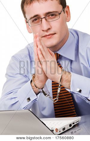 Bonito jovem empresário ligado ao laptop com algemas