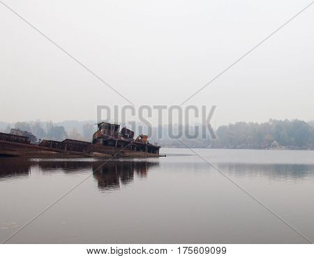 Old rusty sunken ship in water in a foggy day.