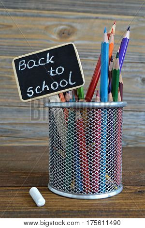 Colored pencils and back to school text written on blackboard