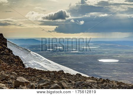 View from the vulcano Ok to lakes in the tundra landscape and the Atlantic Ozean. Moody sky with raining clounds and sunlight.