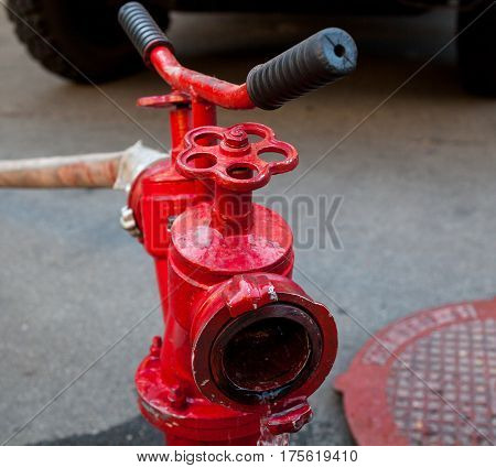 Red fire hydrant with connected hose. Close-up.
