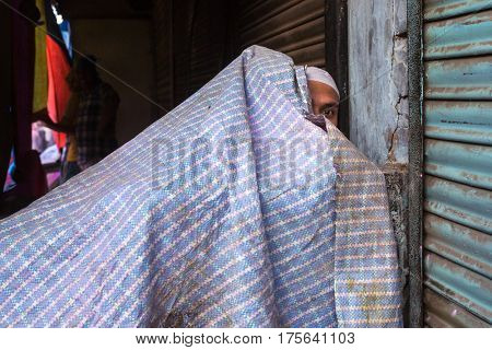 Mathura, India - March 23, 2016:  Unidentified muslim man hide under the plastic tent during Holi celebration in Mathura, Uttar Pradesh, India.