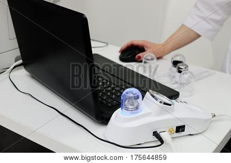 Doctor looking at the laptop results of examination of the patient. Trihoskopiya - examination of hair with the help of a special device