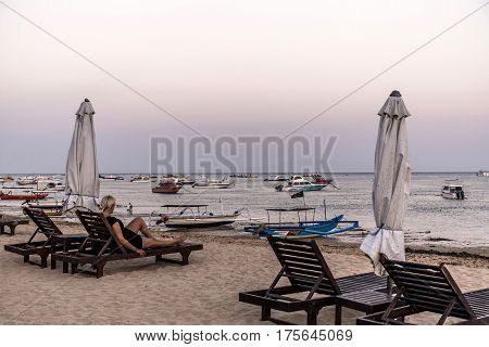 Bali in Indonesia girl sitting at Sanur Beach sunset